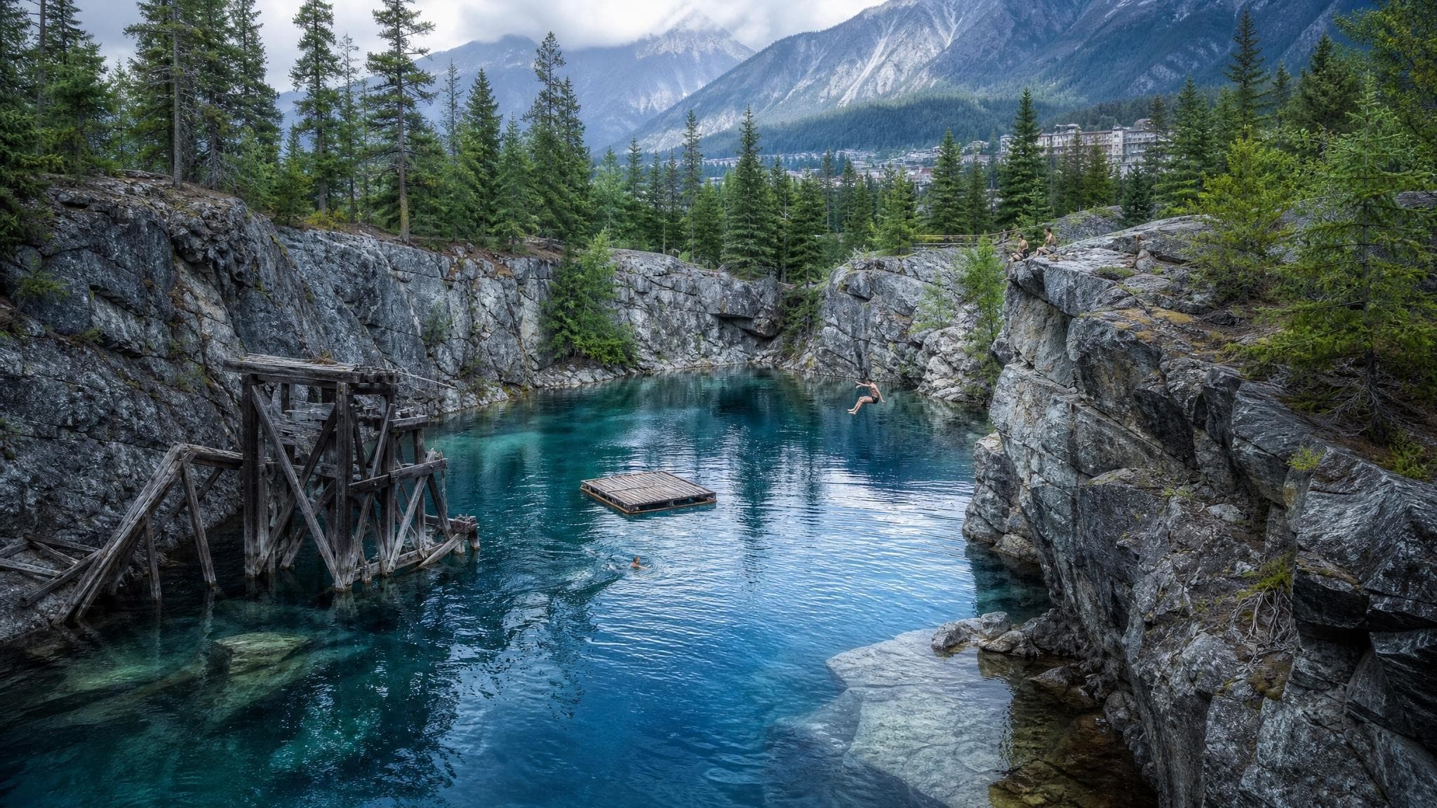 Sheer rock walls dropping into the silver-blue water of Quicksilver Cove, with a floating dock and cliff-jump ledges